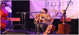 Young Begley plays guitar whilst holding a microphone stand in her mouth at last year’s event.